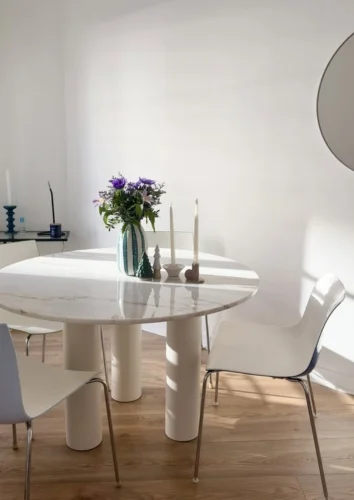 Salle à manger. Table à manger ronde avec plateau en marbre blanc soutenu par 3 pieds de table cylindriques crèmes 16 cm de diamètre LE DÉVOUÉ